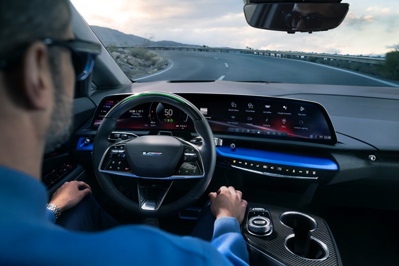 Front View of the 2026 OPTIQ-V Driving Through the Dusk Utilizing its Headlights | Al Serra Cadillac in Grand Blanc MI