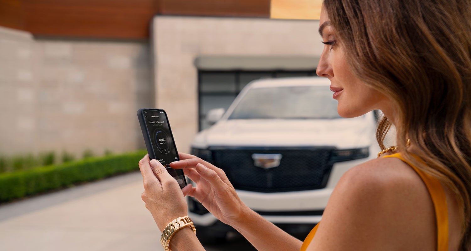 lady checking her mobile with a Cadillac vehicle background | Al Serra Cadillac in Grand Blanc MI